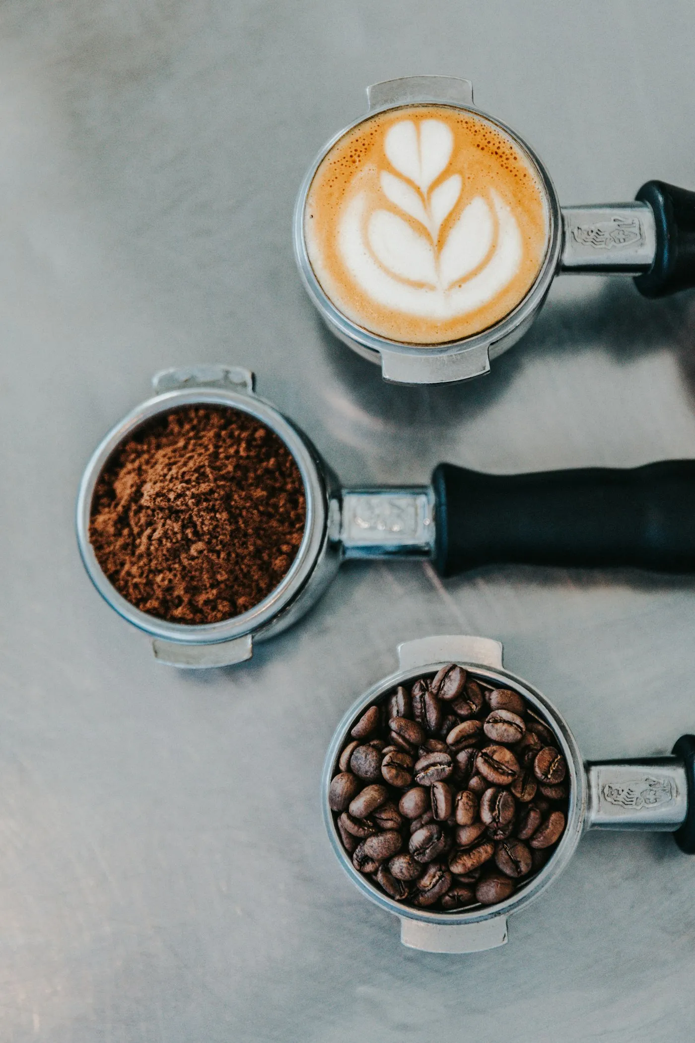 Drie portafilters met verse koffie op een stalen werkblad